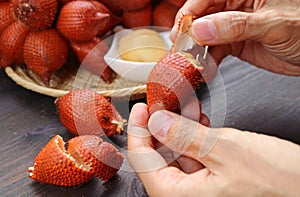Hand Pulling the Tip of Snakeskin Fruit to Peel It Off photo