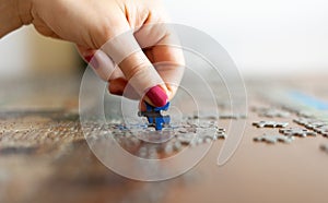 Hand with pink nails while putting the puzzle together