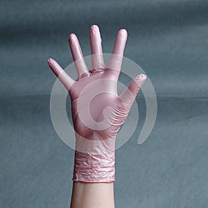 Hand in pink nitrile glove on a gray background with a gradient