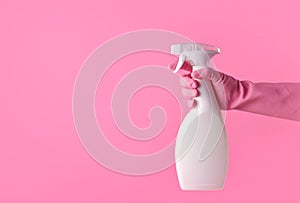 Hand with pink rubber glove holding spray bottle