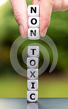 Hand places three dice on a stack and changes the word `toxic` to `non toxic