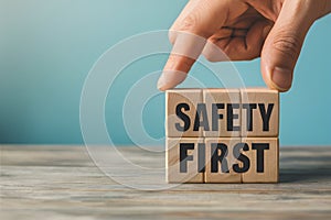 Hand places wooden block with SAFETY FIRST on blue background, promoting security