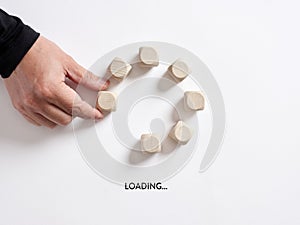 Hand places a wooden cube in loading progress indicator bar with the word loading