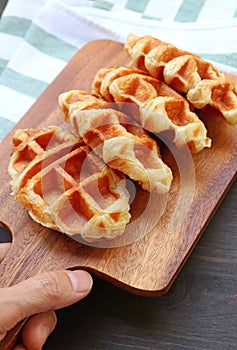 Hand Placing a Breadboard of Croffles on Kitchen Table