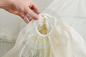 hand placing a delicate garment into a mesh laundry bag