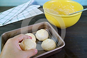 Hand placing dough in the baking tray for baking Brazilian cheese bread photo