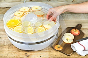 Hand placing fruit slices in food dehydrator