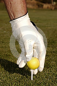 Hand placing golf ball on a tee