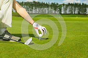 Hand placing golf ball on tee