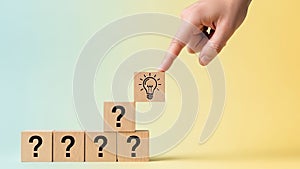 Hand Placing Idea Lightbulb Block on Stack of Question Blocks