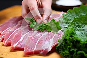 hand placing a leaf of shiso under sashimi slice