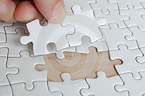 Hand placing missing jigsaw puzzle pieces. Solution concept