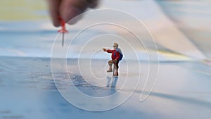 hand placing a red pin with traveler miniature mini figure with