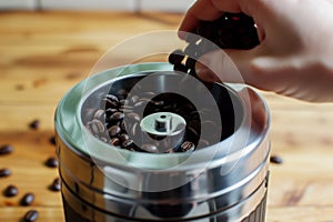 hand placing whole coffee beans into a manual burr grinder