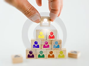 A hand placing a wooden block with people icon onto many others, putting the right man into the right position, HR concept,