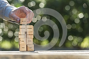 Hand placing wooden building blocks to success