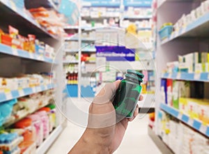 Hand with plastic pill bottle on pharmacy store