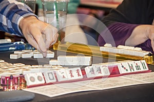 Hand of player reaching for tile in a game of Mahjong - selective focus
