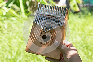 Hand playing kalimba or mbira is an African musical instrument.made from wooden board with metalInstrument in garden