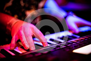 Hand Playing Keyboard Keys in Bright rainbow pink stage Lights