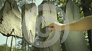 Hand plays on sounding stones. Shorted stones hung on string like musical drumming tool.