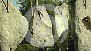 Hand plays on sounding stones. Shorted stones hung on string like musical drumming tool.