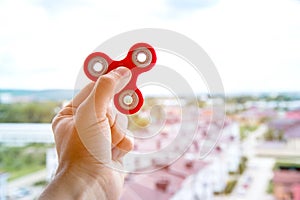 The hand plays with a spinner against the background of the urban landscape in the city fidgeting hand toy