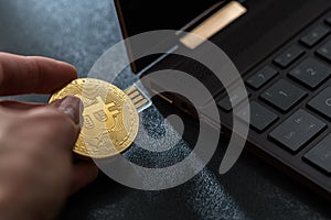 A hand plugging in a Bitcoin thumb drive into windows laptop