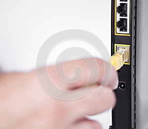 hand plugging ethernet cable into router. High quality photo