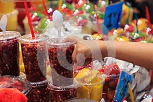 Hand pointing glass full of fresh fruit, put on the market of La Boqueria, an old traditional market in Barcelona.