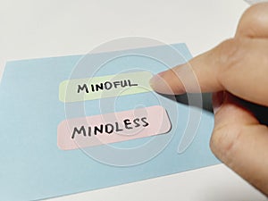 Hand pointing at a note showing the words Mindless and Mindful