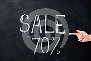 Hand pointing at seventy percent sale drawn on blackboard