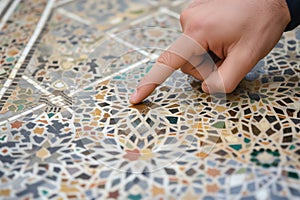 hand pointing at specific features of an intricate inlaid tile sample