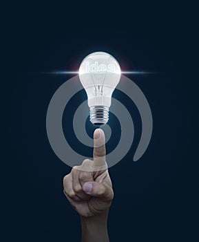 Hand pointing to light bulb with blue spot light and idea word o