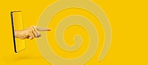 Hand pointing to something by forefinger from smartphone on yellow background