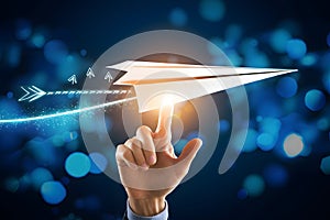 Hand points to paper plane with BUSINESS GROWTH text, symbolizing progress and success on blue bokeh background