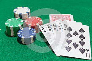 Hand of poker, Royal flush of spades, chips on green background