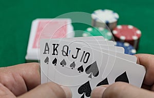 Hand of poker, Royal flush of spades, chips on green background