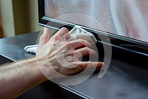 hand polishing a flatscreen television with a dusting cloth