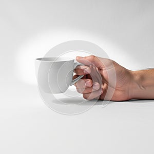The hand is positioned from the side gripping the handle of the mug with the