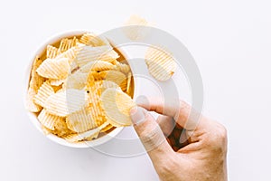 Hand with potato chips and bowl on white background