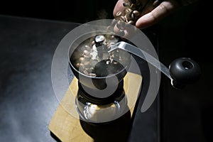 Hand pour coffee beans into grinder with smoke, on coffee drink maker concept