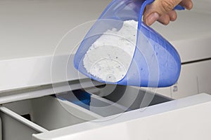 Hand pouring detergent into the washing machine