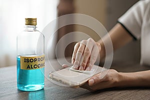 Hand pouring ethyl alcohol from bottle  into a cotton piece for clean mobile phone, corona virus or Covid-19 protection