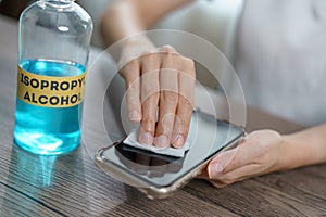 Hand pouring ethyl alcohol from bottle  into a cotton piece for clean mobile phone, corona virus or Covid-19 protection