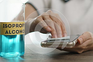 Hand pouring ethyl alcohol from bottle  into a cotton piece for clean mobile phone, corona virus or Covid-19 protection