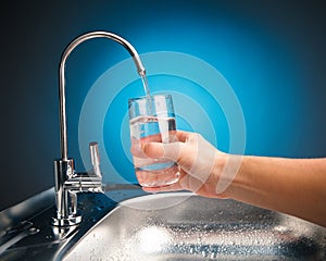 Hand pouring a glass of water from filter tap