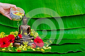 Hand pouring holy water for blessing and pray respects to Buddha statue when Thailand Songkran Festival day