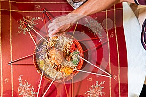 Hand pouring ingredients onto a serving of yusheng or yee sang with raw salmon belly during Chinese New Year for good