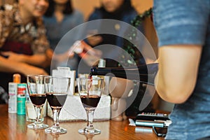 Hand pouring red wine in glass during party with friends.